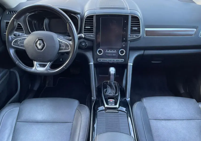 Vue intérieure avant du Renault Koleos 2019, tableau de bord noir avec écran tactile vertical et volant multifonction.
