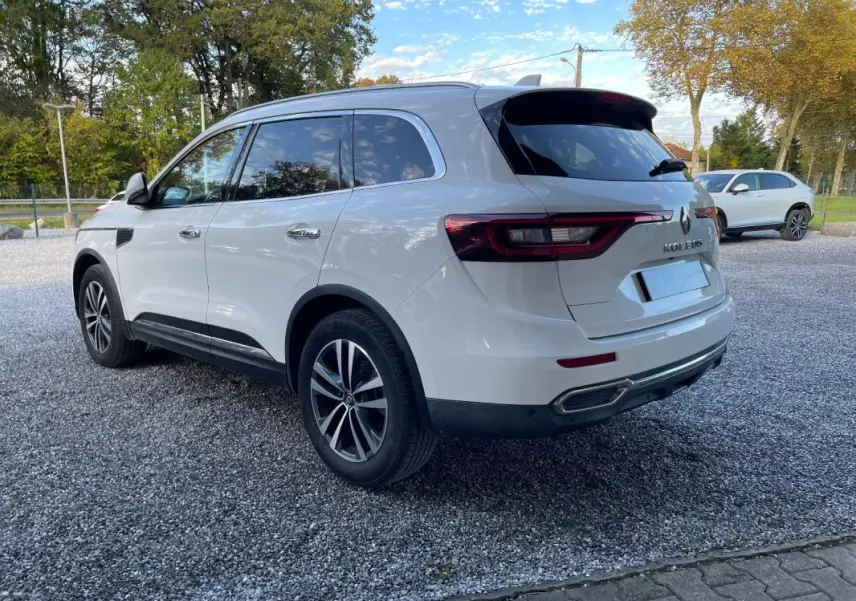 Renault Koleos blanc vu en 3/4 arrière droit, avec feux arrière allongés et jantes alliage distinctives.