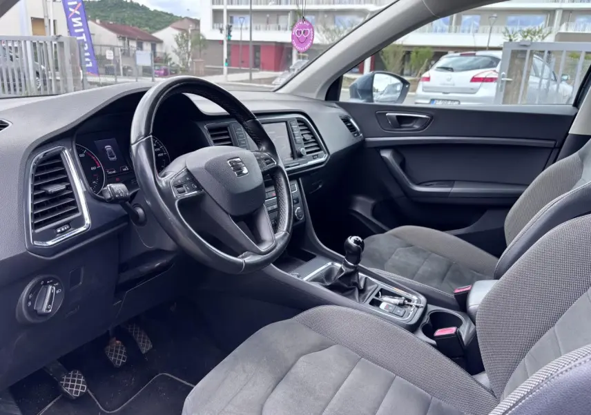 Intérieur avant du SEAT Ateca gris foncé, vue côté conducteur montrant volant cuir et tableau de bord moderne.