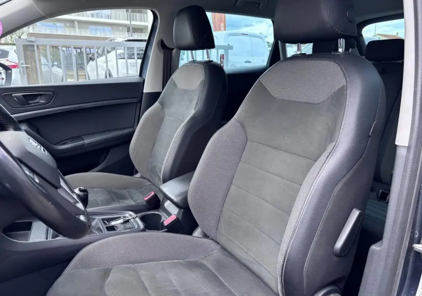 Vue intérieure côté gauche du SEAT Ateca 2019, sièges en textile gris foncé avec accoudoir central.