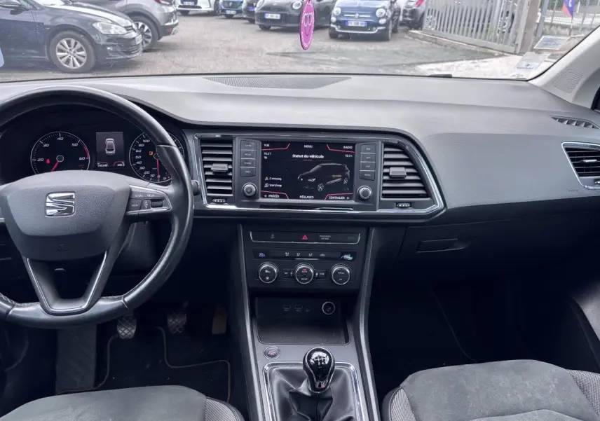 Vue intérieure avant du tableau de bord et volant cuir d'une SEAT Ateca gris foncé avec boîte manuelle et écran tactile central.