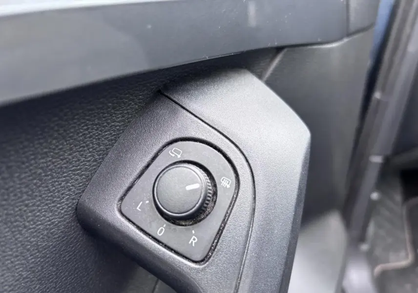 Gros plan sur le bouton de réglage des rétroviseurs côté conducteur du SEAT Ateca gris foncé, intérieur avant gauche.