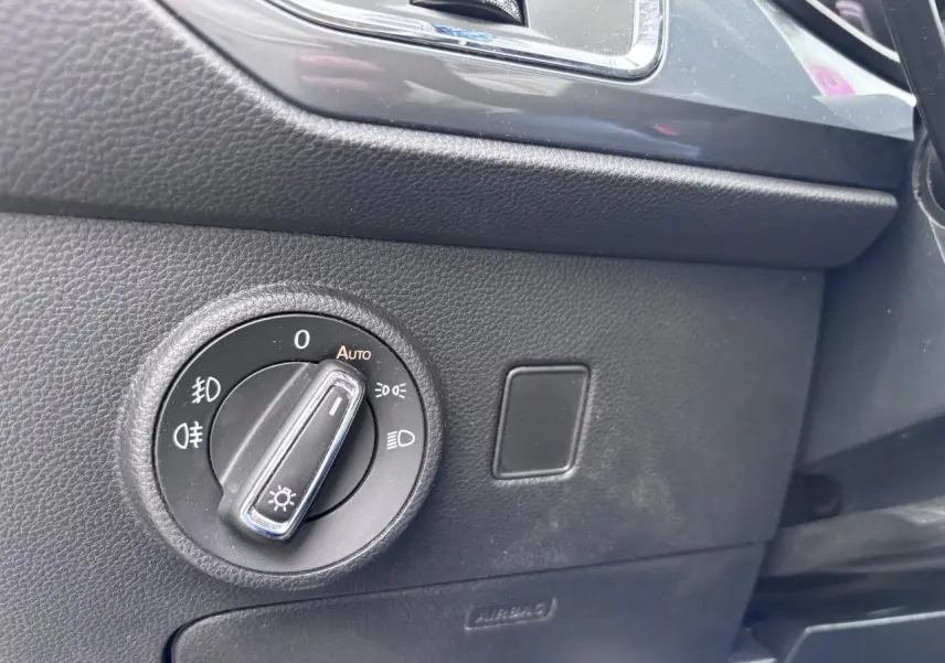 Gros plan sur le bouton de commande des phares à gauche du tableau de bord du SEAT Ateca gris foncé.