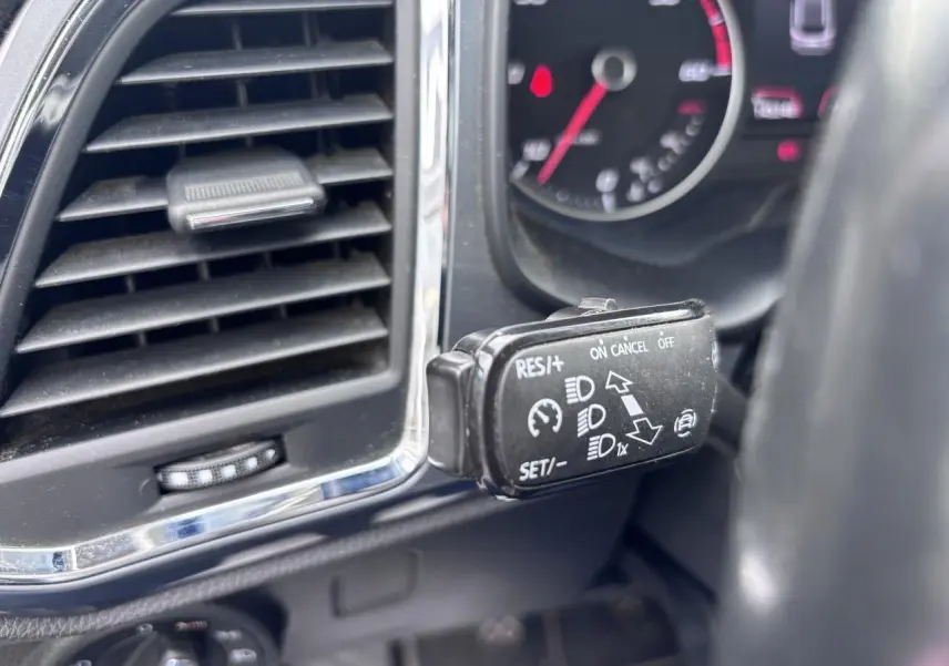 Gros plan sur la commande de régulateur de vitesse à gauche du volant dans l’habitacle gris foncé du SEAT Ateca 2019.