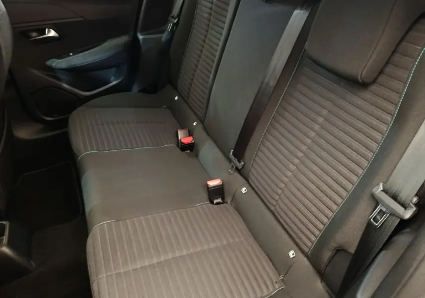 Vue intérieure sur la banquette arrière noire de la Peugeot 208 PureTech 100 S&S Style avec ceintures et appuie-têtes visibles.