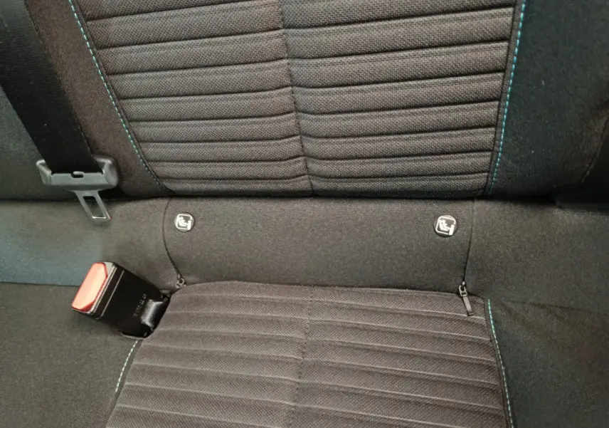 Gros plan sur la banquette arrière noire de la Peugeot 208 PureTech 100 S&S Style avec surpiqûres bleues et attaches Isofix visibles.
