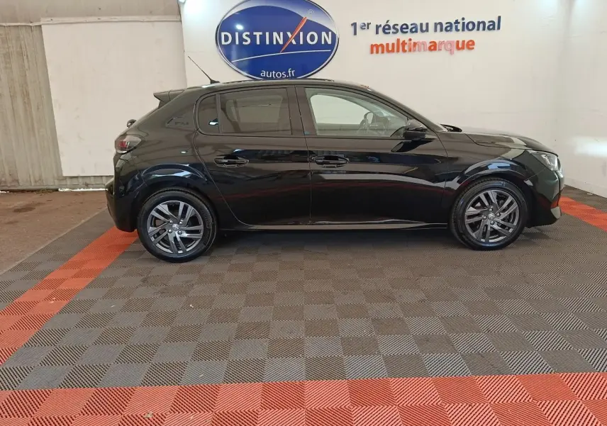 Profil côté gauche d'une Peugeot 208 PureTech 100 S&S Style noire, avec jantes alliage et vitres teintées, en intérieur showroom.