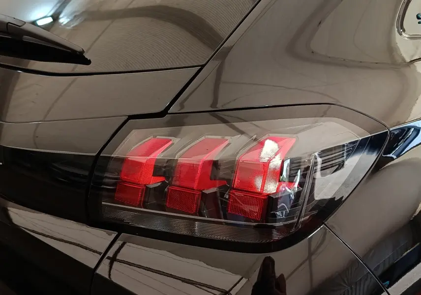 Gros plan sur le feu arrière droit rouge d’une Peugeot 208 PureTech 100 S&S Style noire de 2022.