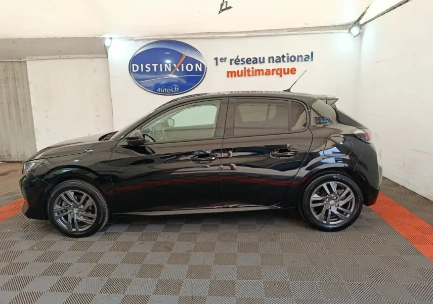 Profil côté gauche d'une Peugeot 208 PureTech 100 S&S Style noire, stationnée en intérieur sur sol damier.