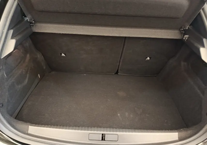 Coffre ouvert de la Peugeot 208 PureTech 100 S&S Style noir, montrant l’espace de chargement vide et la banquette arrière rabattable.