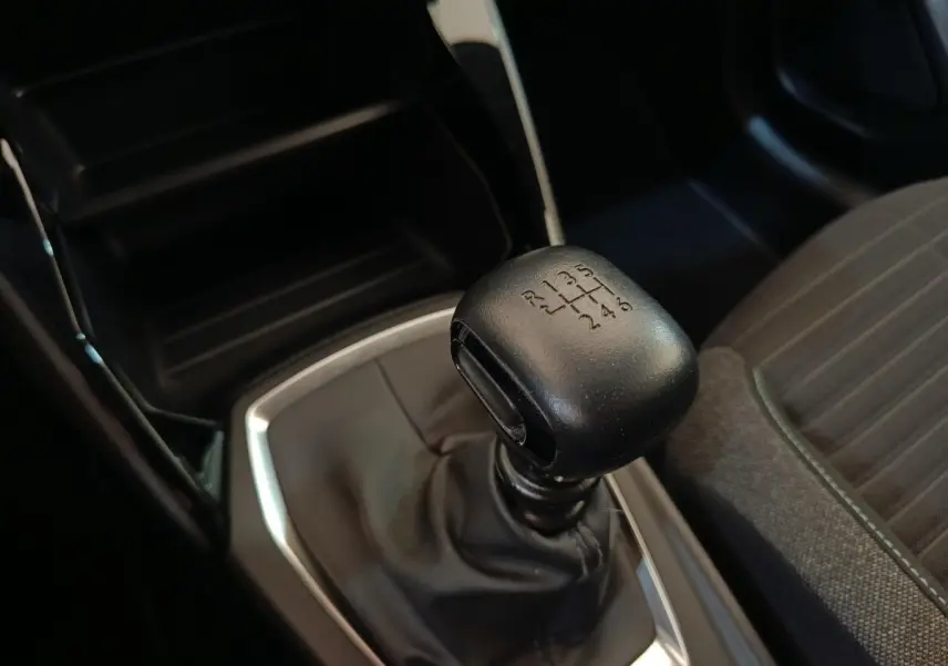 Gros plan sur levier de vitesses manuel noir dans Peugeot 208 PureTech 100 S&S Style 2022, intérieur sombre.