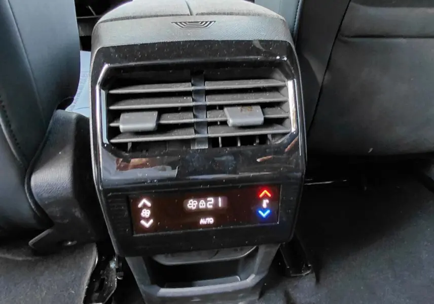 Vue rapprochée de la console arrière grise du Peugeot 5008 Hybrid 2025 avec commandes de climatisation digitale.