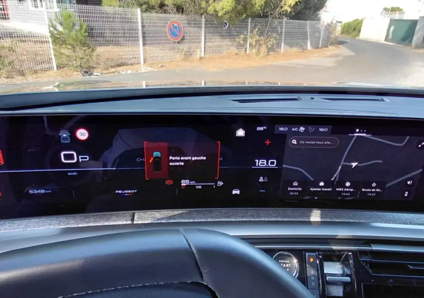 Vue intérieure du tableau de bord numérique du Peugeot 5008 gris 2025, affichant la navigation et alertes portes ouvertes.