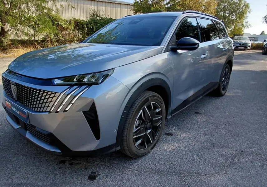 Peugeot 5008 Hybrid gris en 3/4 avant droit, avec calandre distinctive et jantes noires modernes.