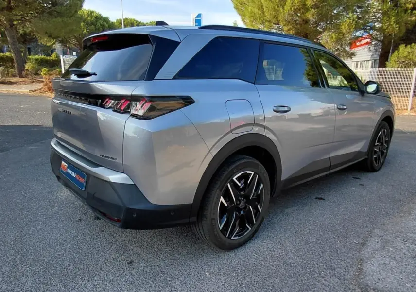 Peugeot 5008 Hybrid gris 3/4 arrière droit, mettant en valeur ses feux arrière distinctifs et ses jantes noires.