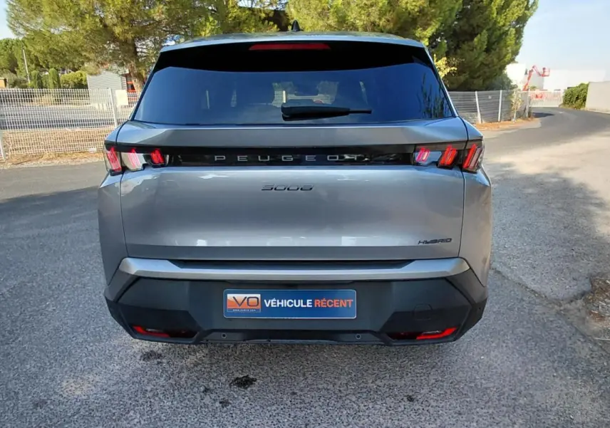 Vue arrière d'un Peugeot 5008 gris 2025 avec feux arrière à griffes et logo Peugeot lumineux.
