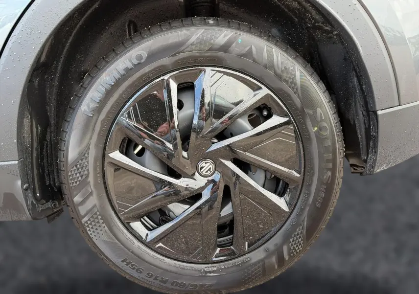 Gros plan sur la roue avant droite du MG ZS Camden grey, jante alliage noire brillante avec logo MG central.