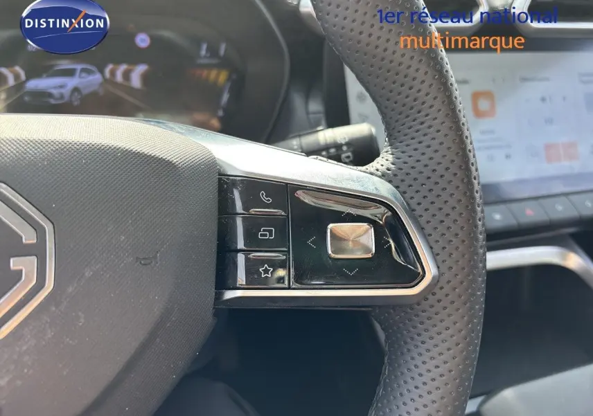 Gros plan sur le volant perforé noir du MG ZS 1.5L Hybrid+ 2025 avec commandes intégrées et tableau de bord numérique en arrière-plan.