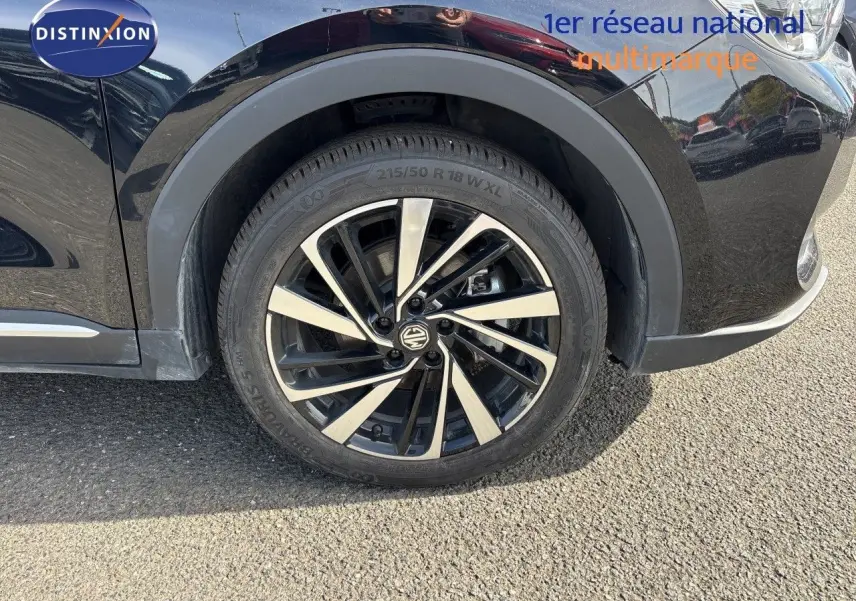 Gros plan sur la roue avant droite du MG ZS 1.5L HYBRID+ 197CH Luxury en Pebble Black Metal avec jante alliage bicolore.
