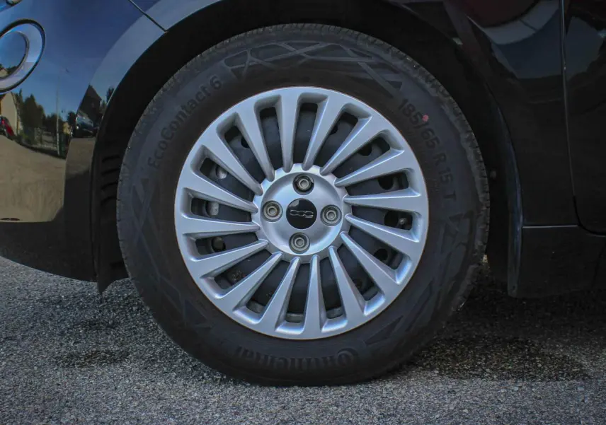 Gros plan sur la jante alliage 15 pouces argentée avec logo 500 au centre du Fiat 500 noir électrique.
