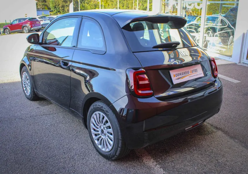 Vue 3/4 arrière droite de la Fiat 500 électrique noire 2023 avec jantes alliage et feux arrière LED distinctifs.