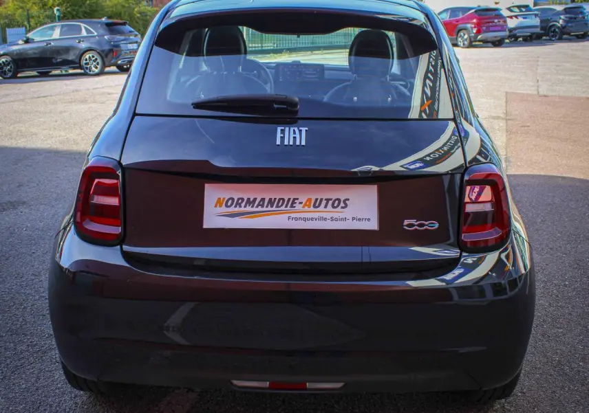 Vue arrière d'une Fiat 500 électrique noire avec logos FIAT et 500, stationnée en extérieur.