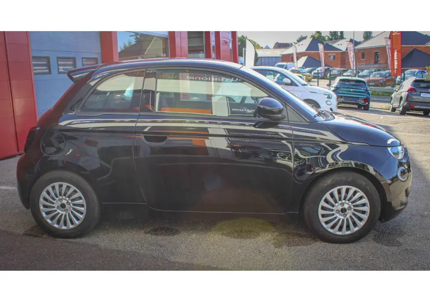 Profil côté gauche de la Fiat 500 électrique 2023 noire, avec jantes alliage et poignées de portes dissimulées.