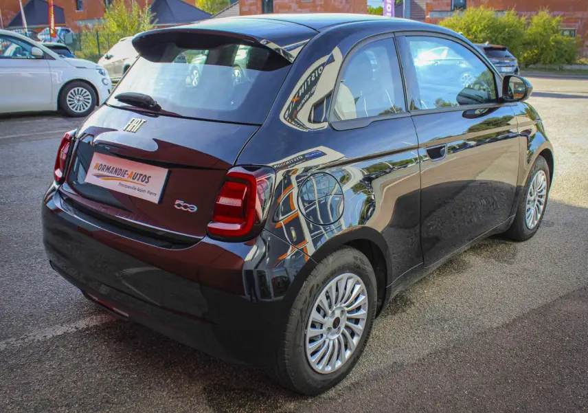 Vue 3/4 arrière droite de la Fiat 500 électrique noire 2023 avec jantes alliage et logos chromés distinctifs.