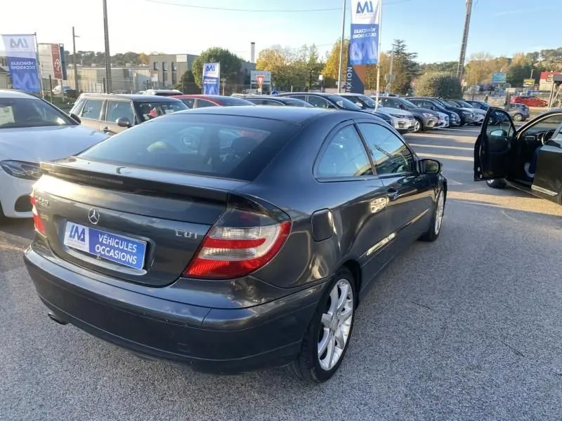 Vue 3/4 arrière droite d'une Mercedes Classe C Coupé Sport 220 CDI gris foncé métal stationnée en extérieur.