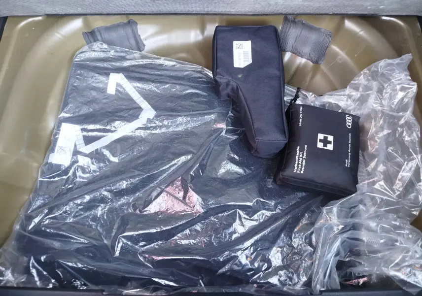 Vue plongeante sur le coffre d'un Audi Q2 35 TFSI noir, montrant des accessoires emballés et une trousse de secours noire.