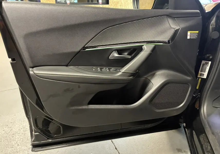 Vue rapprochée de la porte avant gauche noire du Peugeot 2008 1.5 BlueHDi 130 GT Line, avec garniture tissu et commandes électriques.