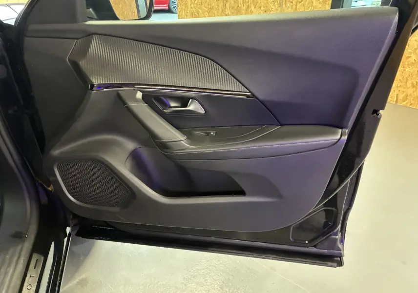 Vue rapprochée de la porte avant gauche noire du Peugeot 2008 1.5 BlueHDi 130 GT Line avec garniture texturée et poignée intégrée.