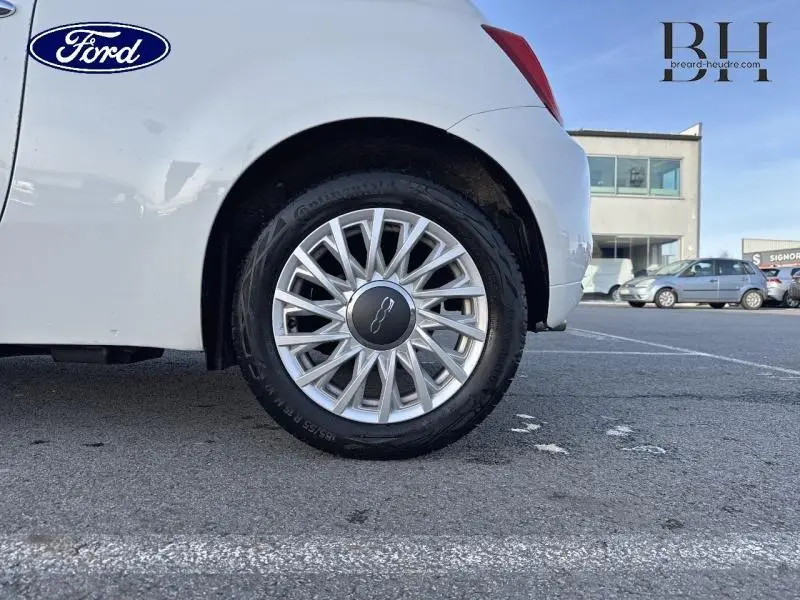 Gros plan sur la roue arrière droite d'une FIAT 500 blanche Bossa Nova avec jante alu au design étoilé.