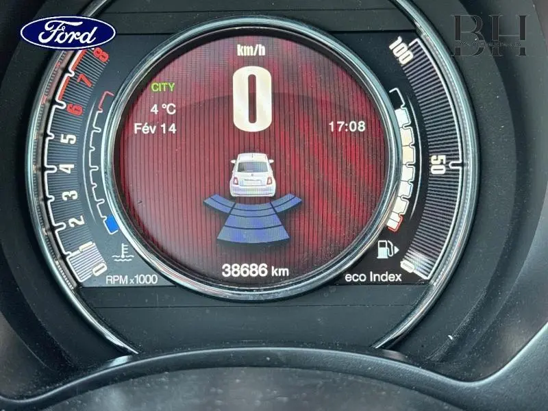 Vue rapprochée du compteur digital de la Fiat 500 blanche, affichant 0 km/h et le système de radar de recul actif.
