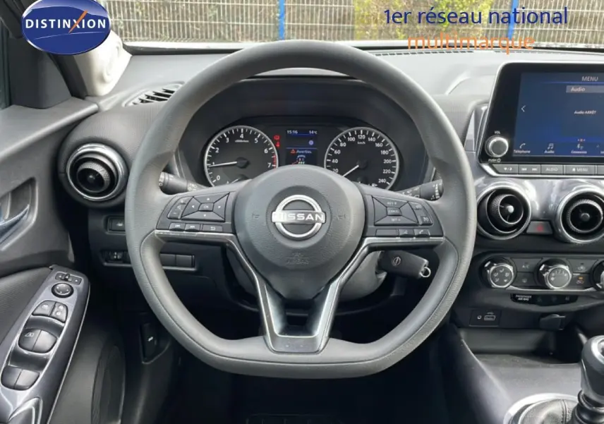 Vue intérieure centrée sur le volant Nissan Juke noir perle 2023, avec tableau de bord et écran tactile visible.