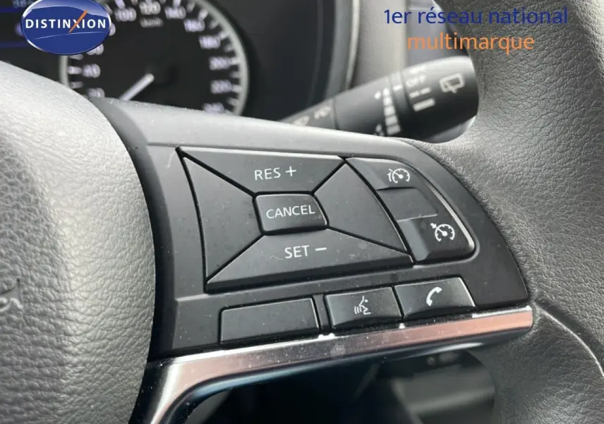 Gros plan sur les commandes au volant noir du Nissan Juke 2023, mettant en valeur les boutons de régulateur de vitesse.