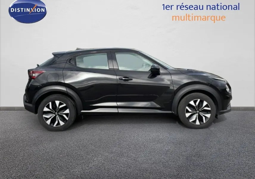 Vue de profil côté gauche d'un Nissan Juke noir perle métal 2023 avec jantes bicolores et lignes dynamiques.