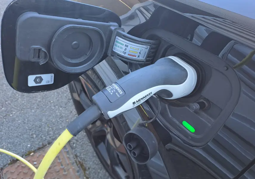 Gros plan sur la prise de recharge côté gauche d’un CUPRA Formentor Noir Minuit avec câble de recharge branché.