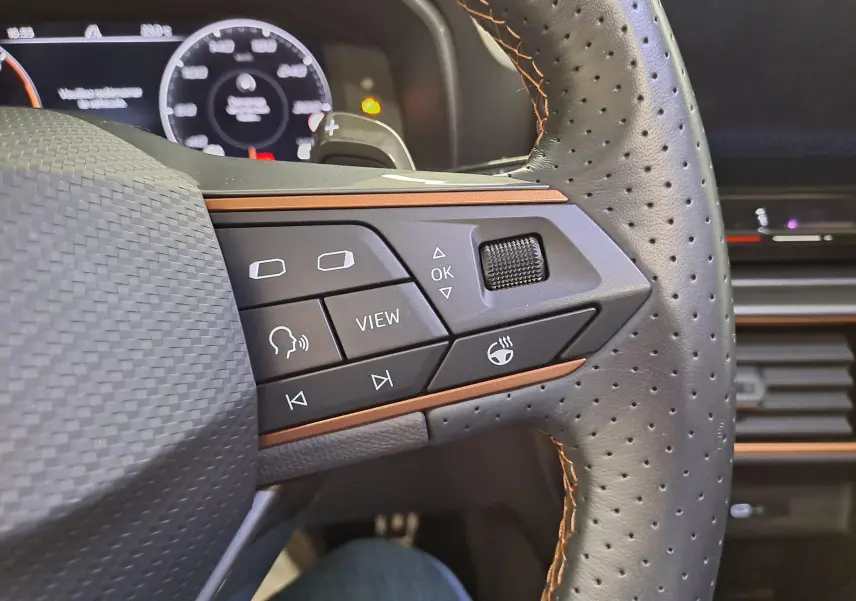 Gros plan sur les commandes du volant en cuir noir perforé avec surpiqûres copper du CUPRA Formentor 2023.