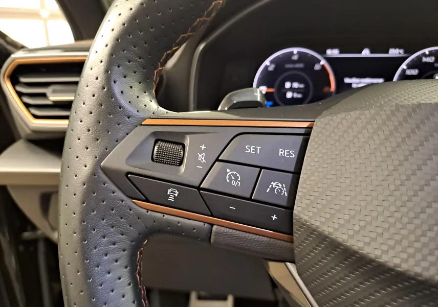 Gros plan sur les commandes à gauche du volant perforé avec surpiqûres copper du CUPRA Formentor 2023 noir minuit.