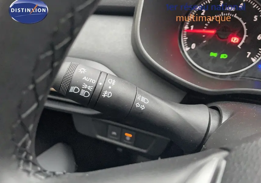Gros plan sur la commande des feux et clignotants à gauche du volant du Dacia Jogger gris schiste, tableau de bord partiellement visible.