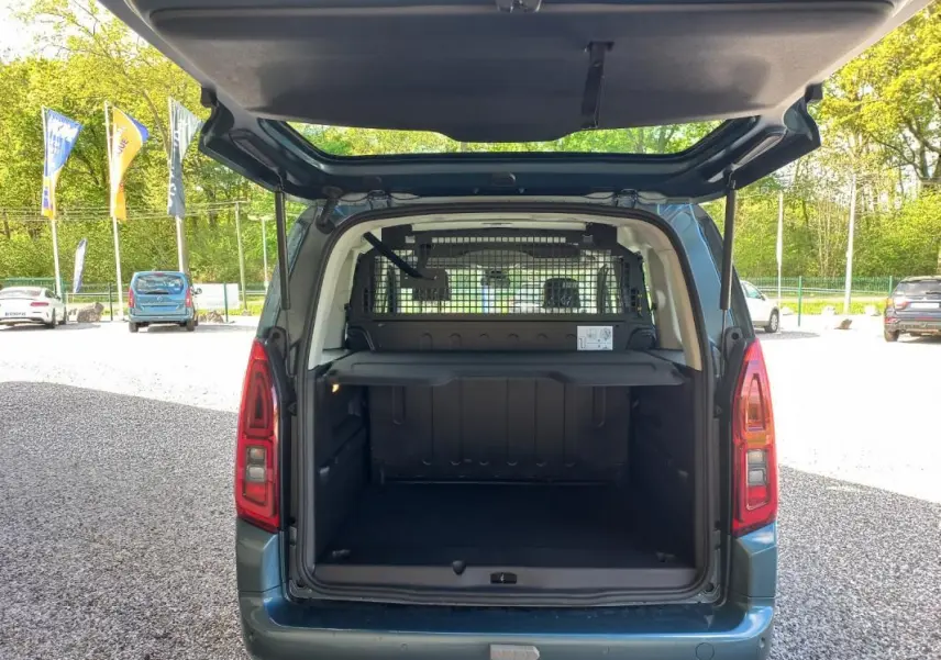 Vue arrière de l’Opel Combo Life Elegance M bleu 2025 avec hayon ouvert montrant l’espace de chargement et la grille de séparation.