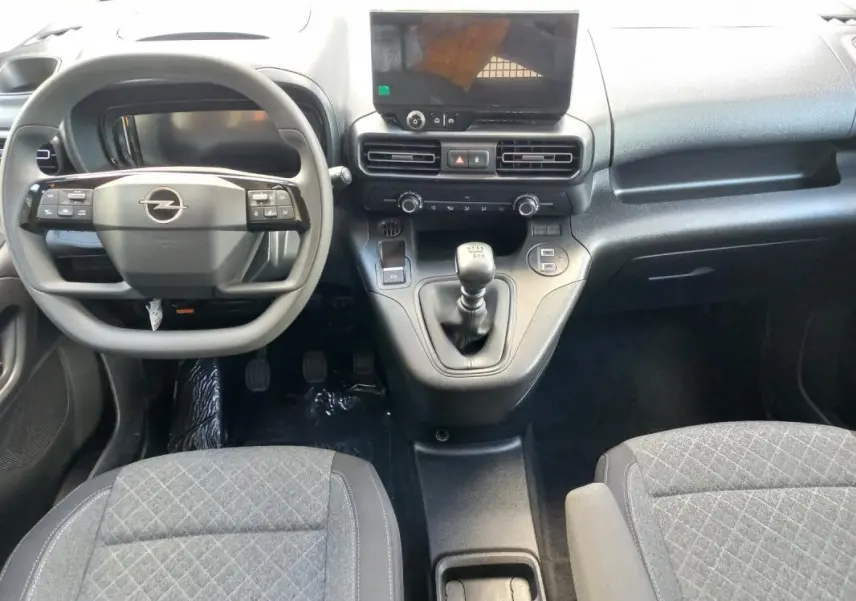 Vue intérieure avant de l’Opel Combo LIFE Elegance M 2025, montrant le volant, la console centrale avec boîte manuelle et sièges gris.