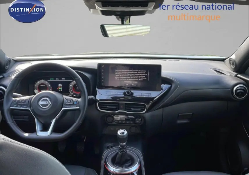 Vue intérieure avant du Nissan Juke 2025 noir Kuro Metal, mettant en valeur le volant, l'écran tactile et la boîte manuelle.