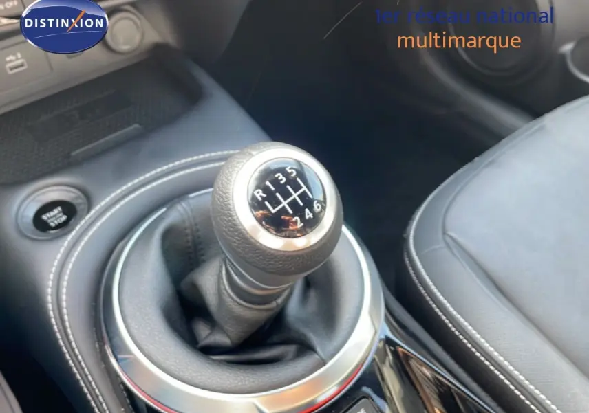 Gros plan sur le levier de vitesses manuel du Nissan Juke 2025 noir Kuro Metal, avec coutures blanches et sellerie cuir noire.