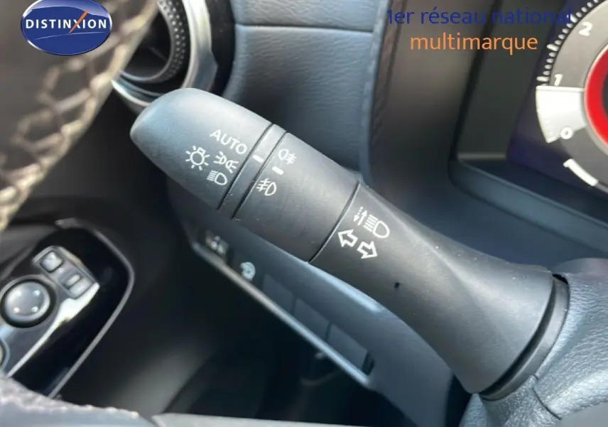 Gros plan sur la commande des feux et clignotants du Nissan Juke noir, intérieur avec volant et tableau de bord partiel.