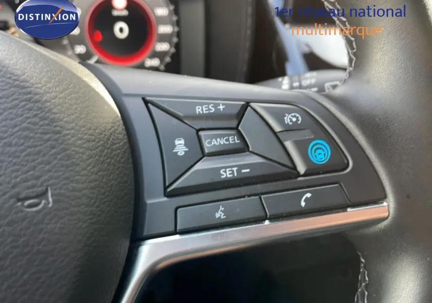Gros plan sur les commandes au volant du Nissan Juke 2025 noir Kuro Metal, avec régulateur de vitesse et commandes vocales.