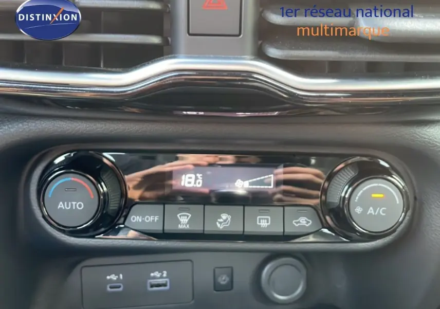 Gros plan sur la console de climatisation digitale du Nissan Juke noir Kuro Metal, affichant 18,6°C et commandes tactiles.