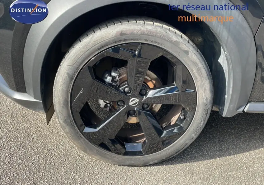 Gros plan sur la roue avant gauche noire brillante du Nissan Juke 2025 en finition Tekna, avec carrosserie noir Kuro Metal.