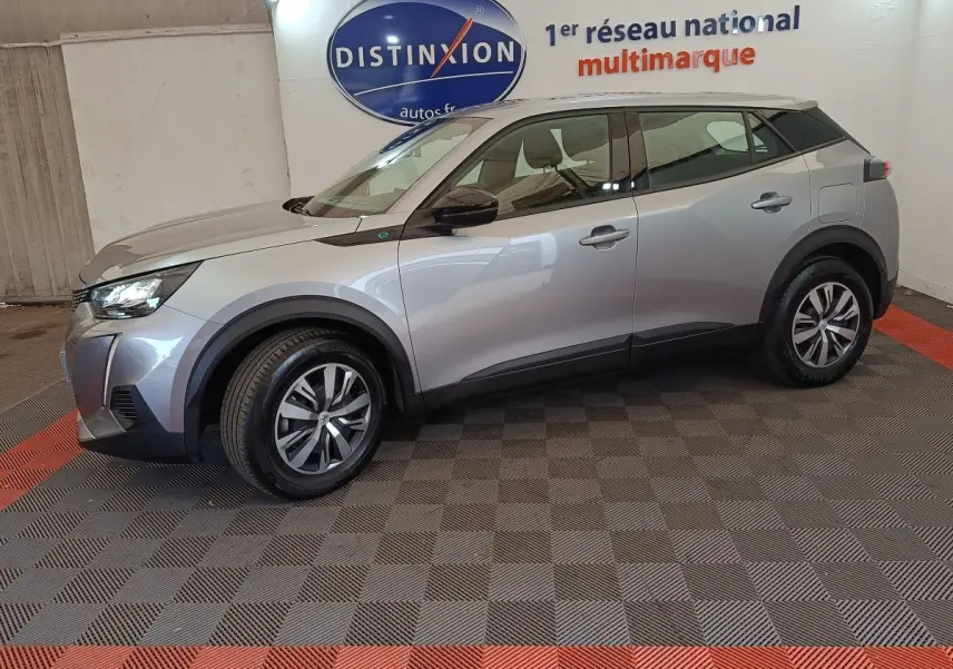 Peugeot E-2008 électrique gris clair vue de profil côté gauche, avec jantes alliage et détails noirs contrastants.